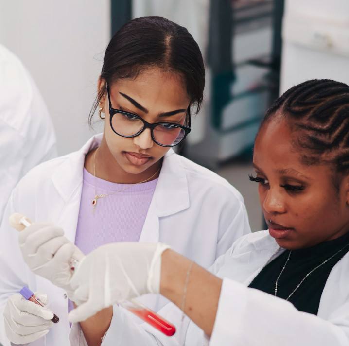 Two lab researchers in white coats handling a test sample
